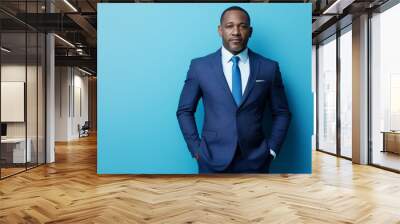 Portrait of confident black man wearing blue suit and light shirt standing against vibrant blue background Wall mural