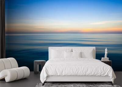 Abstract view of the glassy smooth surface waves of a calm sea during the magic hour of sunrise Wall mural