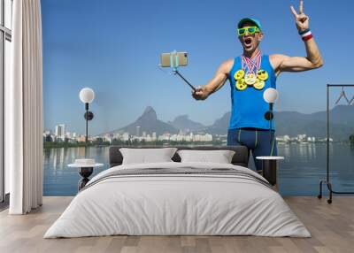 Athlete taking selfie wearing gold medals with bright yellow emoji faces with smartphone on selfie stick in Rio de Janeiro, Brazil Wall mural