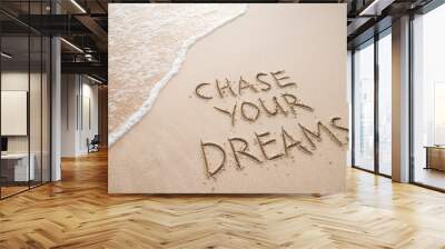 Chase Your Dreams travel message handwritten on smooth sand beach with incoming tropical wave Wall mural