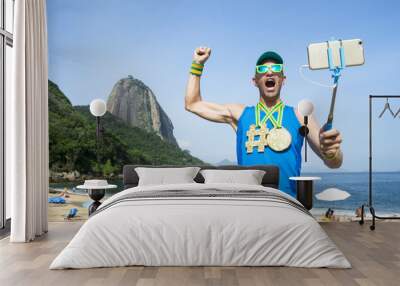 Hashtag gold medal athlete posing for a selfie with his mobile phone on a selfie stick at Praia Vermelha Red Beach in Urca, Rio de Janeiro, Brazil Wall mural