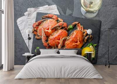 Cooked whole crabs on black plate served with white wine, black slate background, top view Wall mural