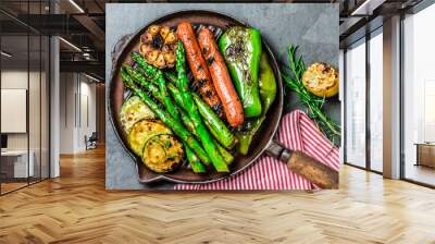 Grilled vegetables and sausages on cast iron grill pan. Gray slate background. Wall mural