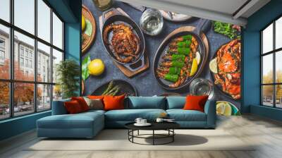 Set table with seafood dishes - cooked crabs, tiger shrimps, grilled octopus and squids on cast iron grilled pans and plates, White wine. Toned photo. Top view Wall mural