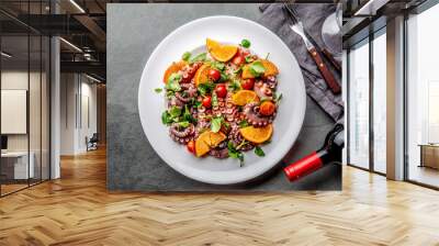 Whole octopus salad with orange, tomatoes and cress salad on white plate. Top view Wall mural