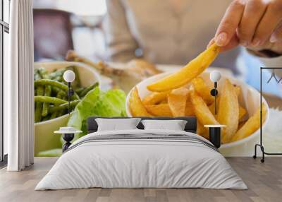 woman eats french fries at restaurant, salad, vegetable Wall mural