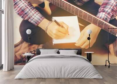 young hipster composing the song with guitar . Wall mural