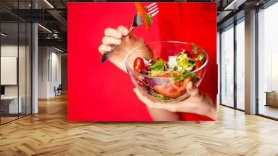 Beautiful caucasian woman eating salad over green natural background	 Wall mural