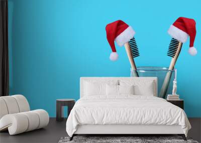 Christmas and New Year holiday background. Xmas greeting card. Bamboo eco friendly toothbrushes with santa hats on blue background  Wall mural