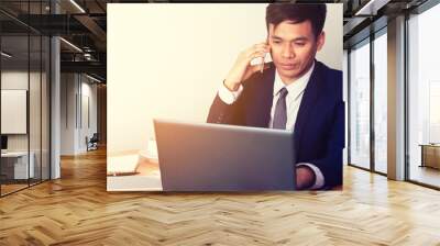 Young businessman looking at the performance of a laptop with a Wall mural