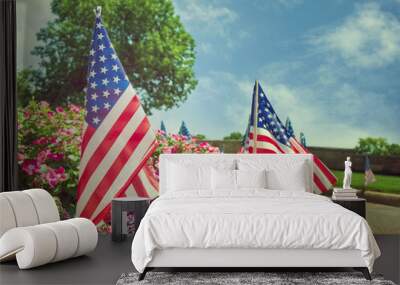 American flags displayed on the side of the street in honor of the 4th of July. Beautiful flower bed and blue sky background. Wall mural