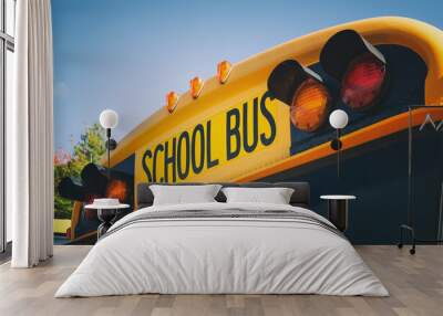 Top of a yellow school bus with lights and text. Closeup against blue sky in the fall. Back to school concept. Copy space. Wall mural