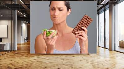 Mature woman, salad bowl or chocolate with selection for diet, pick or choice in studio on a gray background. Female person, nutritionist or model with organic or mix vegetables and slab for decision Wall mural