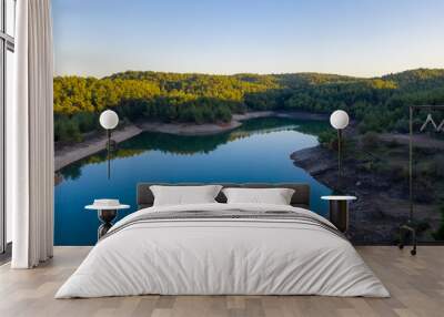 Natural lake surrounded by pine trees, mountains and a village. Wall mural