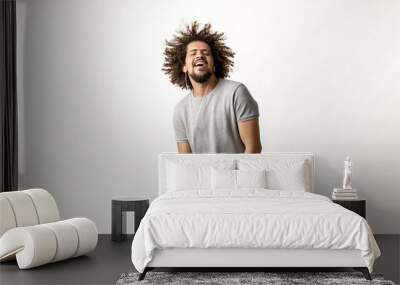 a curly-headed handsome man wearing a gray t-shirt and ripped jeans is listening to music in the ear Wall mural