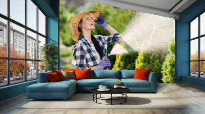 Beautiful young gardener woman watering garden in hot summer day Wall mural