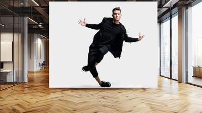 Dark-haired stylish young dancer wearing a black sweatshirt and black pants makes stylized movements of street dances Wall mural