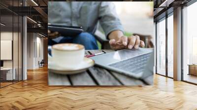 A man working outdoor on old wooden table with coffee drink using laptop working or meeting online, freelance work, part time job Wall mural