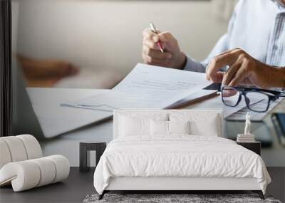 Asian businessman reviewing document reports at office workplace with computer laptop. legal expert, professional lawyer reading and checking financial documents or insurance contract before sign Wall mural