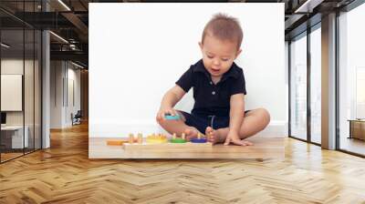 2 year old boy sitting at home on the floor and playing with wooden blocks Wall mural