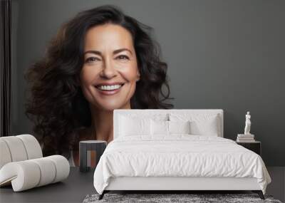 A beautiful Latina woman in her 50s smiles brightly against a grey backdrop Wall mural