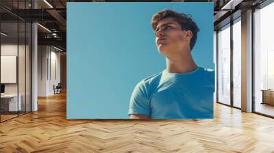 A young man wearing a blank t-shirt stares at the blue sky Wall mural