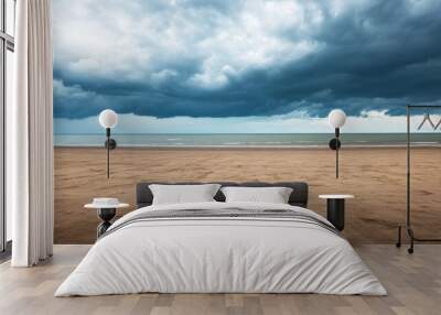 Waves gently lap at the shore as dark clouds gather ominously overhead at the beach Wall mural