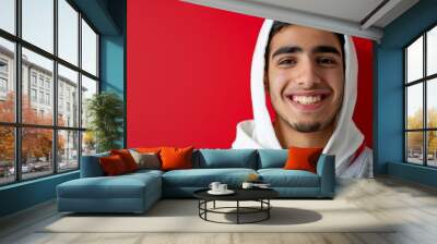 Young Muslim male in hoodie smiling warmly at camera Wall mural