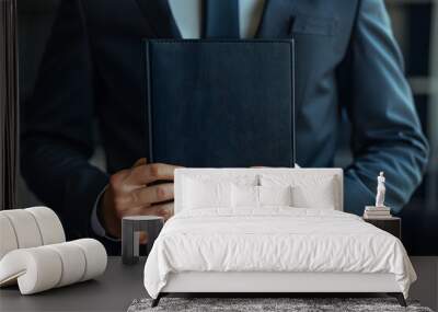 Man in suit holding a black book with both hands Wall mural