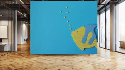 toy yellow and blue fish swims in the blue water and blows bubbles. Childhood toy. Concept sea and holiday Wall mural