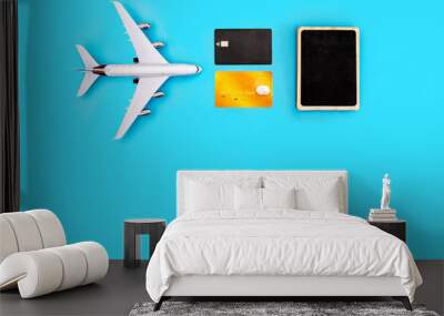 plane, credit cards, and a sign for writing on a blue background. The picture symbolizes the vacation planning and the cost of air travel Wall mural