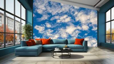 Looking up at fluffy white clouds and a blue sky Wall mural