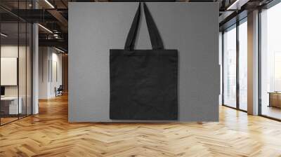 Black fabric bag on dark background. Canvas handbag hanging on cement wall. Wall mural