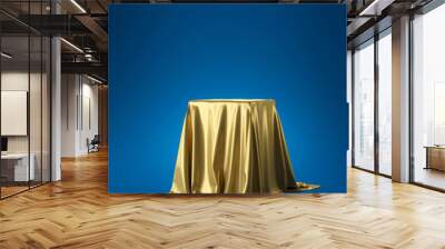 Golden luxurious fabric or cloth placed on top pedestal or blank podium shelf on blue background with luxury concept. Museum or gallery backdrops for product. 3D rendering. Wall mural