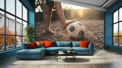 Poor kid playing old soccer or football on ground with glowing sunlight background and hope concept. Wall mural