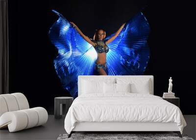 Belly dancer woman in blue costume with wings on dark background Wall mural