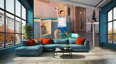 Tennage girl doing fitness gymnastics at home. Gymnastics exercises video tutorial. Children's activity in quarantine during coronavirus pandemic concept Wall mural