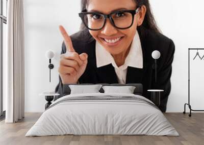 top view of smiling asian businesswoman with eyeglasses pointing finger up, isolated on white background in full body Wall mural