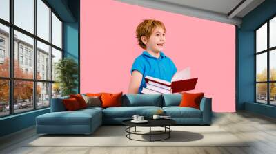 Blonde boy in t-shirt reading a book thirsty for knowledge on pink background. Wall mural