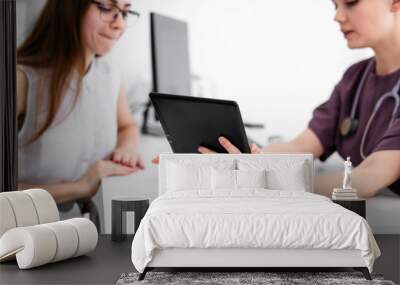 Close up of female doctor and patient sitting at the desk in modern clinic. Wall mural