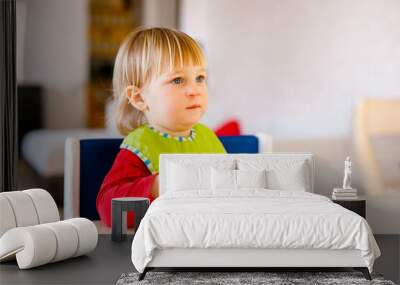 Cute baby 1,4 years old sitting on high children chair and eating vegetable alone in white kitchen Wall mural