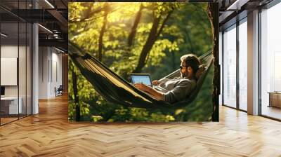 portrait of a European man lying in a hammock with a laptop in nature. remote work Wall mural