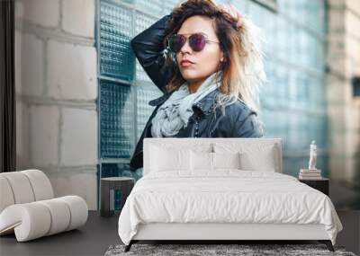 attractive fashion model in mirrored sunglasses, a black leather jacket, black jeans near brick wall. Wall mural