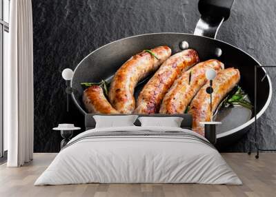 Delicious pork chipolatas sausages in a frying pan on black stone background Wall mural