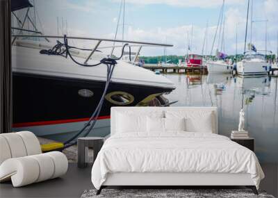 close up view on bow of moored motorboat on quayside with jetty ful of sailing yachts on background Wall mural