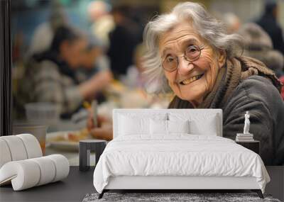 Cheerful elderly homeless woman eats free meal in spacious dining hall. Old lady in need visits soup house to get food. Volunteer care of houseless Wall mural