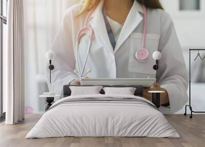 Doctor wearing a pink ribbon stethoscope using a digital tablet in a hospital room Wall mural