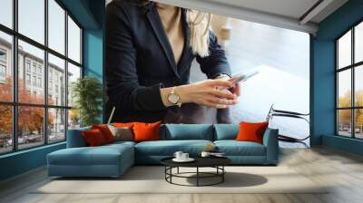 unrecognizable blonde business woman in suit with phone sitting at a table in a cafe, close up Wall mural