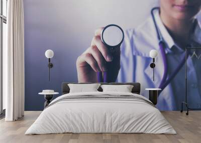 A young female doctor listening ,holding medical stethoscope Wall mural