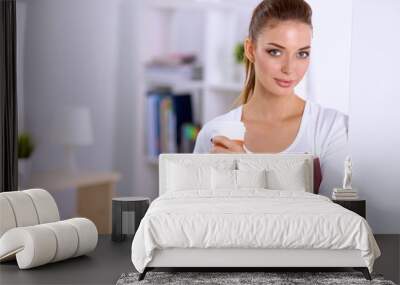 Attractive young businesswoman standing  near wall in office Wall mural